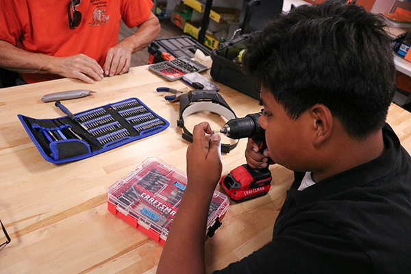 A boy uses a drill 