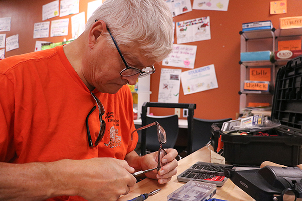 A man works to screw a pair of glasses back together