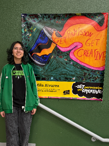 A girl smiles next to her artwork
